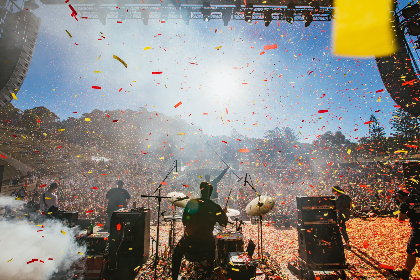 A huge crowd on the hill at Splendour in the Grass Music Festival watching a band rock out with confetti sprinkling down